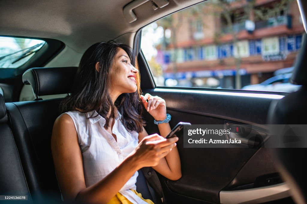 Ung kvinna Vacationer med smart telefon i baksätet av Taxi