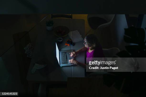 overhead view of senior woman using her laptop at night - makeshift desk stock pictures, royalty-free photos & images