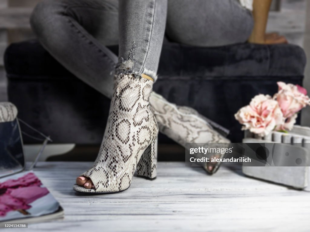 Lyx kvinnliga hög klack skor gjorda av orm hud som bärs av en kvinna