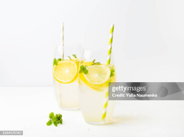 summer drinks. homemade lemonade or alcoholic cocktail with lemon, mint or lemon balm in glass glasses on a light background. - limonade stockfoto's en -beelden