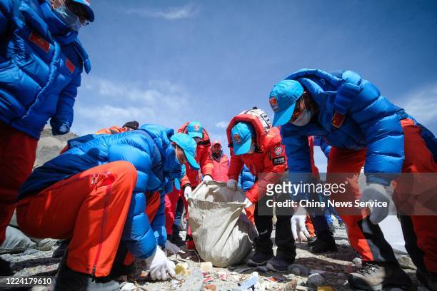 Climbers collect garbage prior to a ceremony to mark the 60th anniversary for human beings to reach the summit of Mount Qomolangma, or Mount Everest,...
