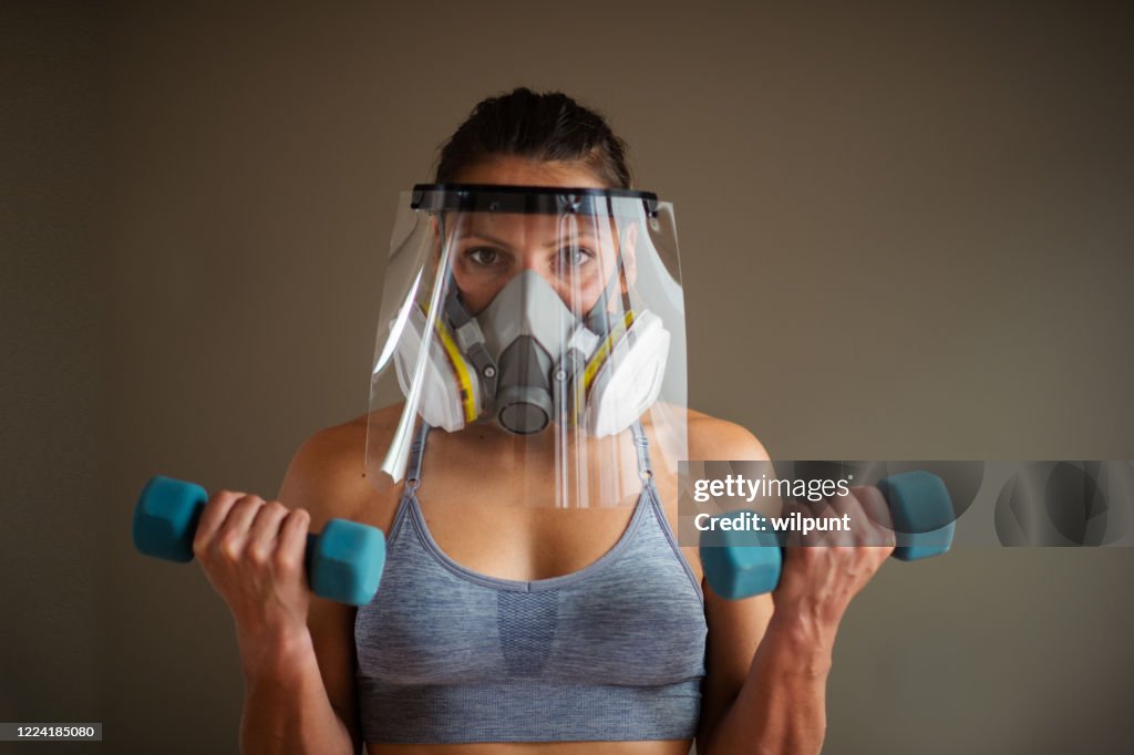 Protective face gear muscular young woman bicep curl portrait