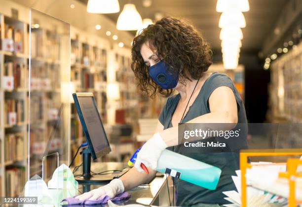 small business woman owner disinfecting pexiglass wall - retail covid stock pictures, royalty-free photos & images