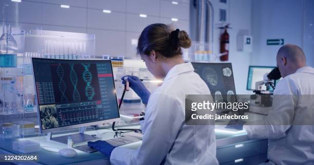multi ethnic research team studying dna mutations. female doctor in foreground - research stock pictures, royalty-free photos & images