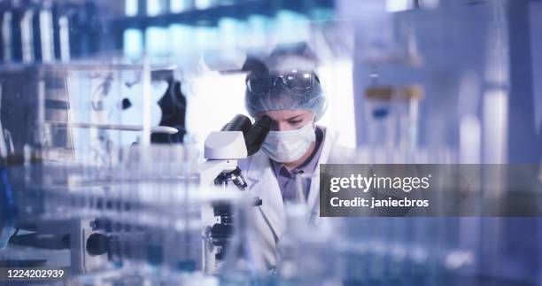 giovane microbiologa donna che studia il coronavirus - abbigliamento da lavoro protettivo - laboratorio chimico foto e immagini stock