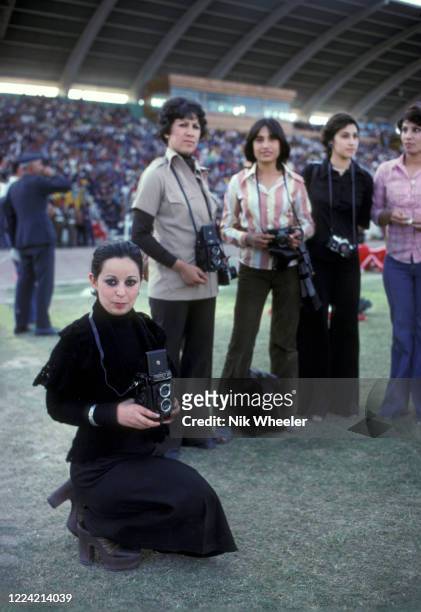 Iraqi women photographers stand on touchline inside the National Stadium during a soccer match in Baghdad, circa 1978