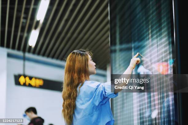 businesswoman using a large touch screen in the subway station - interaktivität stock-fotos und bilder