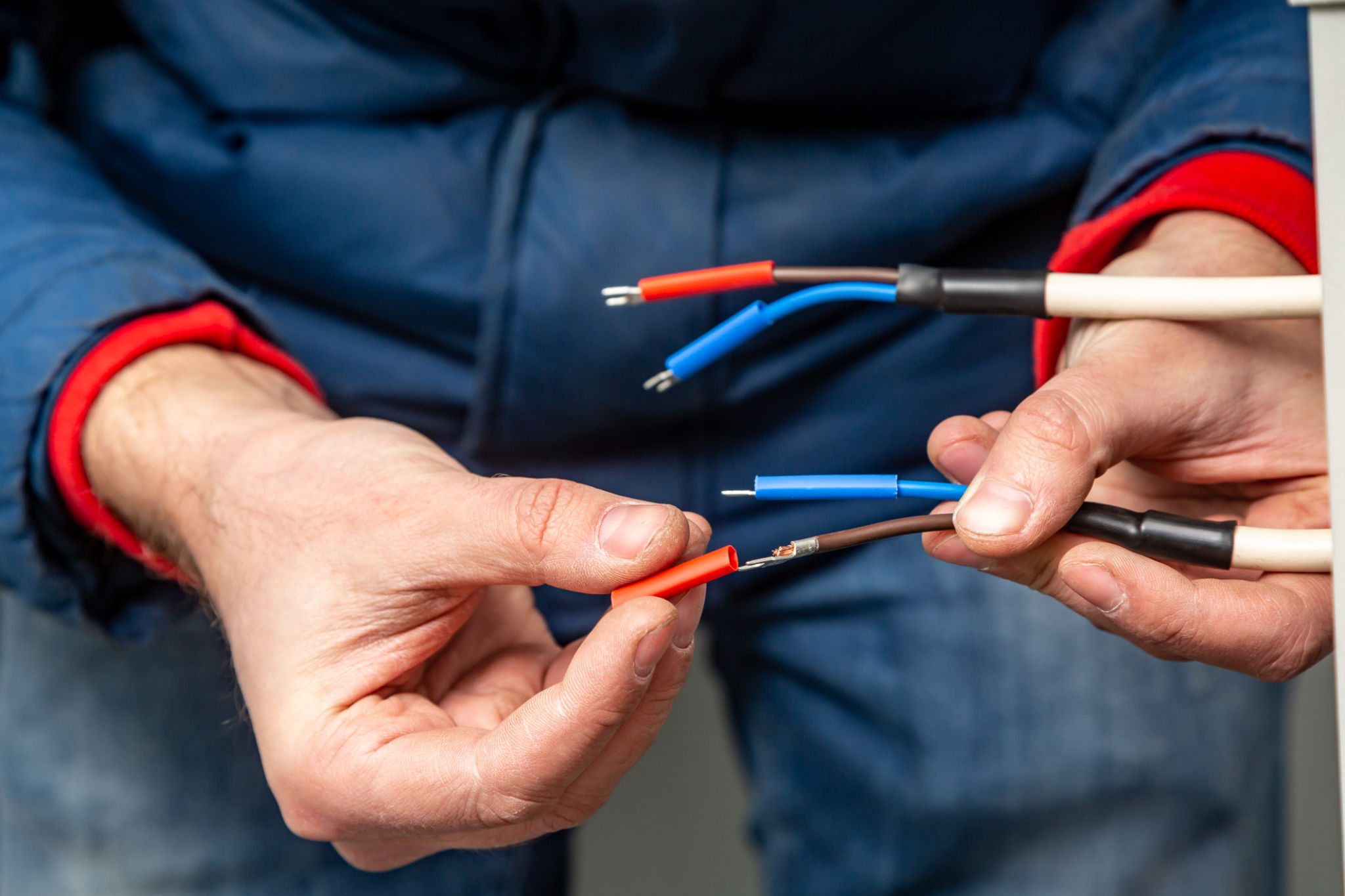 Hands putting insulation on wires. Red, blue, white.Close-up. Horizontal orientation Hands putting insulation on wires. Red, blue, white.Close-up. Horizontal orientation