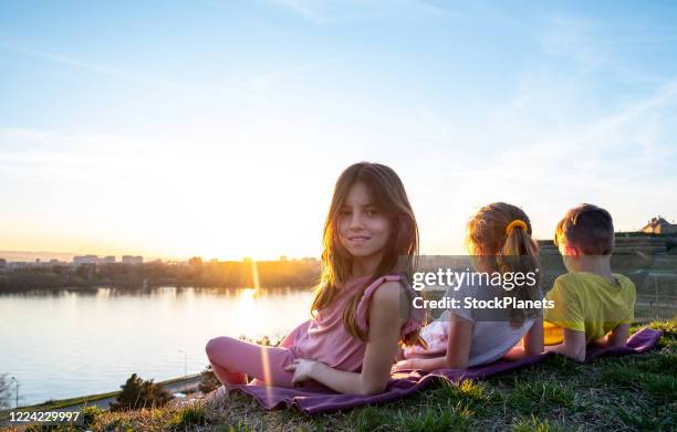 kids enjoying looking sunset from viewpoint - triplet girls stock pictures, royalty-free photos & images