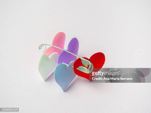 hearts attached with safety pin. polyamory concept - polygamie stockfoto's en -beelden