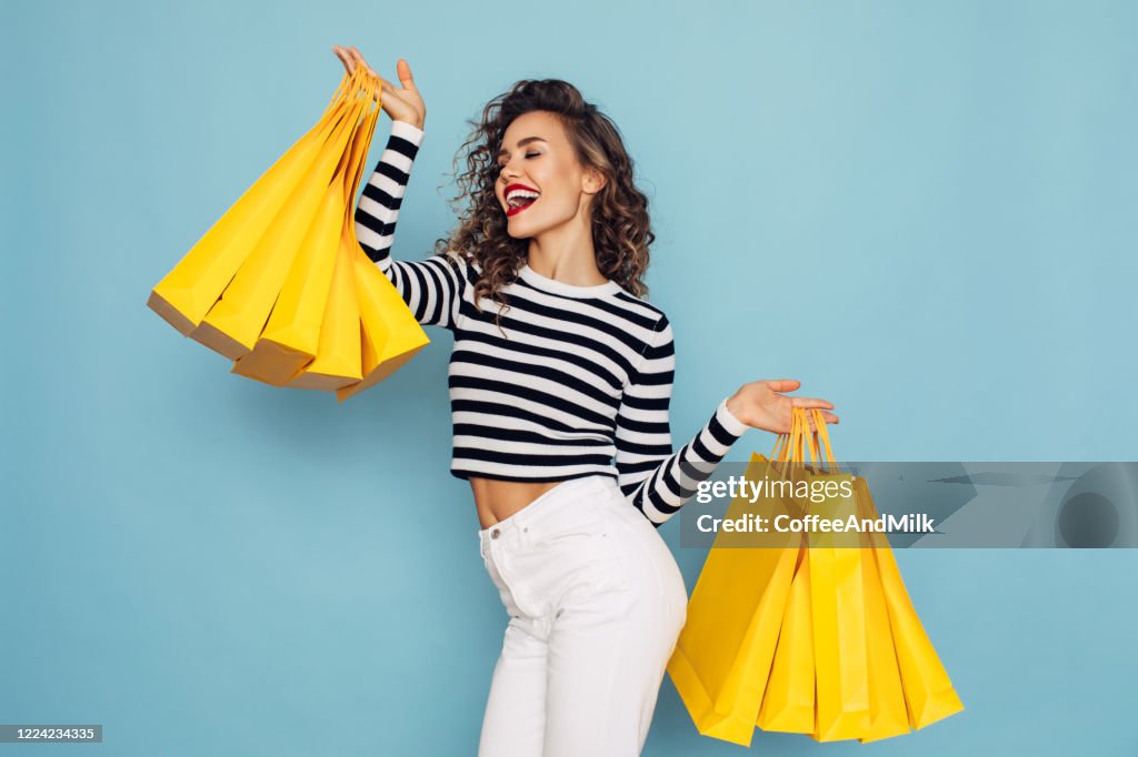 Konzeptfoto von glücklichen Mädchen hält Einkaufspakete auf blauem Hintergrund