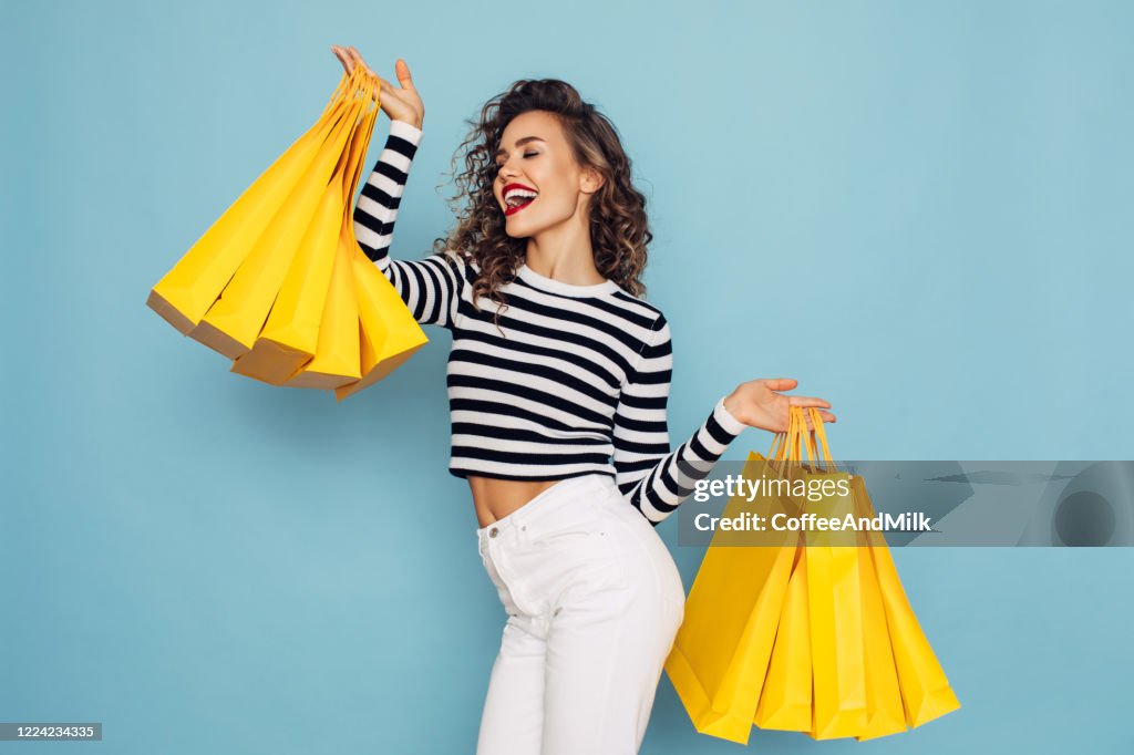 Foto conceptual de chica feliz tiene paquetes de compras en fondo azul