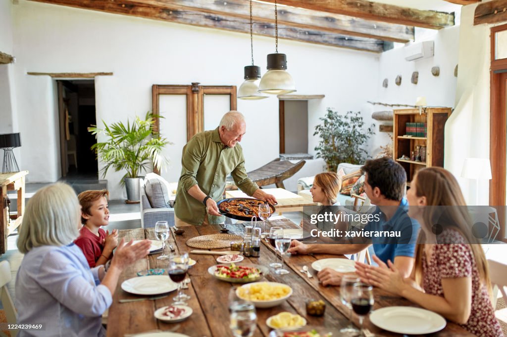 Senior Man Receiving Applause for Traditional Spanish Paella