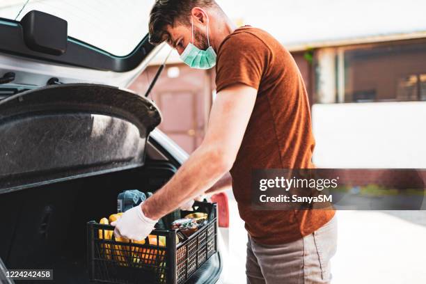 entregador com máscara de proteção e luvas entregando mantimentos durante o confinamento e pandemia - driving mask - fotografias e filmes do acervo