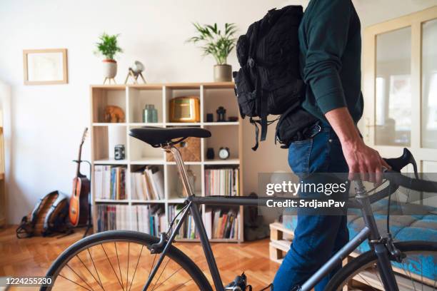 man with a backpack and a bicycle leaves his apartment - leaving apartment stock pictures, royalty-free photos & images