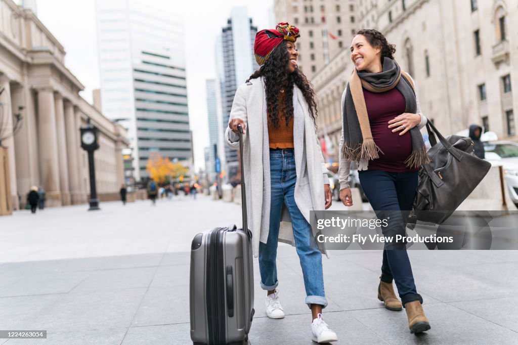 Pregnant woman with female friend exploring city while on vacation