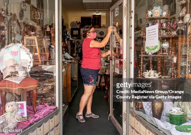 Lisa Baldwin, owner of A & P Collectables, cleans the front door at her Old Towne Orange antique store in Orange on Thursday, May 7, 2020 as she...