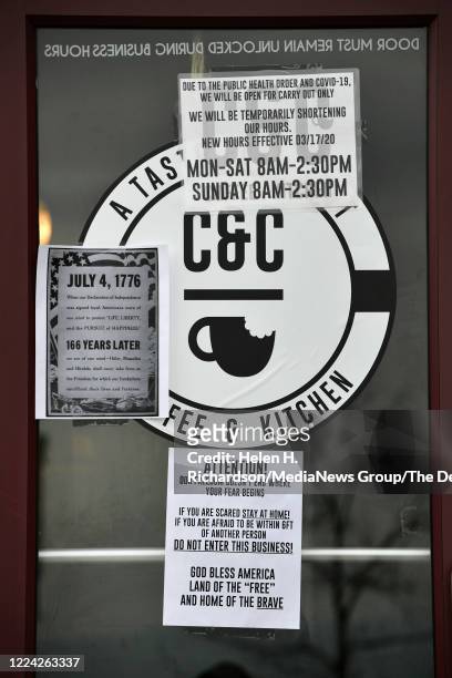 Signs hang on the side door of the C&C Coffee & Kitchen on May 11, 2020 in Castle Rock, Colorado. The cafe decided to open to the general public and...