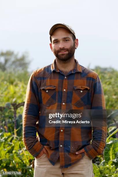 portrait of a male millennial farmer, wearing a plaid top and baseball cap, stands near his organic farm during the end of the summer. - camisa a cuadros fotografías e imágenes de stock