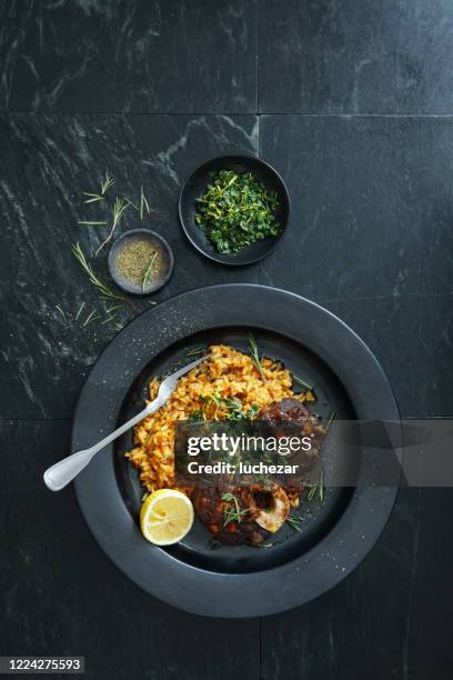 traditioneller italienischer osso buco mit cremigem safranrisotto und gremolata - osso bucco stock-fotos und bilder