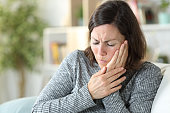 Middle age woman suffering toothache at home
