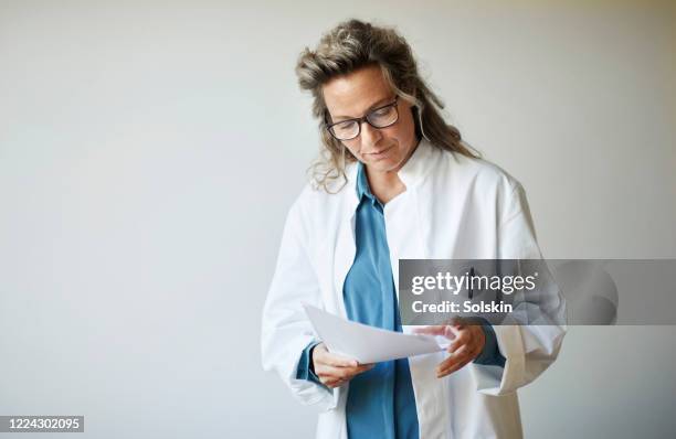 female doctor looking at patient documents - quarantaine stockfoto's en -beelden