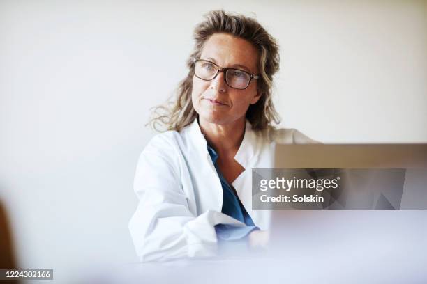 female doctor using laptop - gezondheidszorg en medicijnen stockfoto's en -beelden