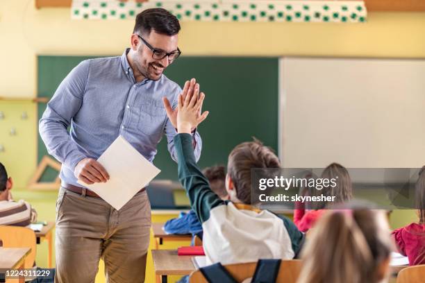 glad lärare och skolpojke ger varandra high-five på en klass. - teacher man bildbanksfoton och bilder