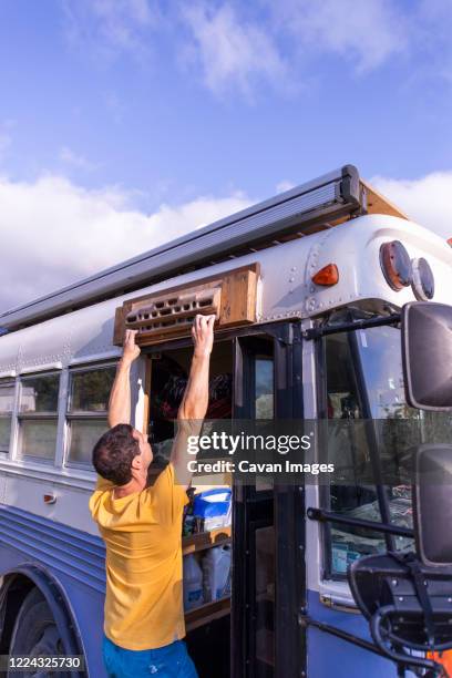 climber hangboarding on a converted school bus in front of door - exercice physique stockfoto's en -beelden