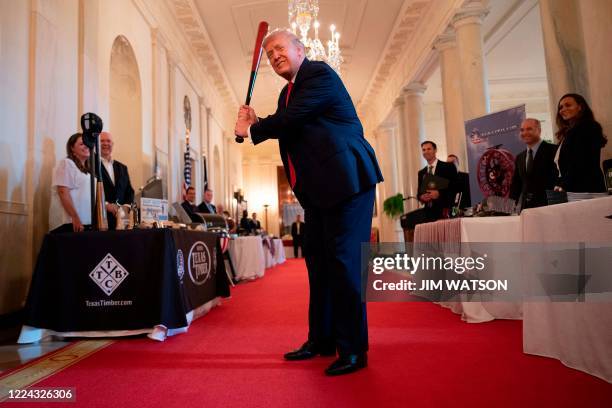 President Donald Trump takes a swing with a bat from Texas Timber before speaking at a Spirit of America showcase event to spotlight small businesses...