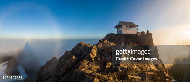 hikers stand at sunrise outside three fingers lookout, north cascades - 監視塔 ストックフォトと画像