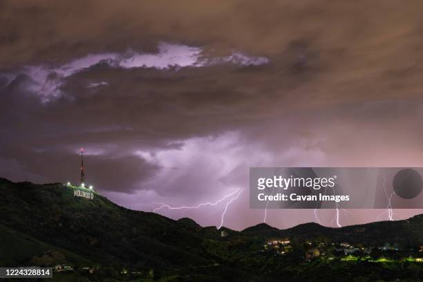 lightning strike silhouetting the hollywood sign in los angeles - hollywood sign at night - fotografias e filmes do acervo