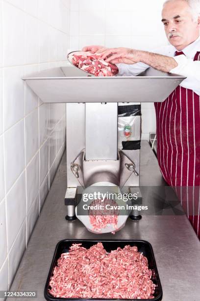 butcher grinding meat in shop - trituradora de carne fotografías e imágenes de stock