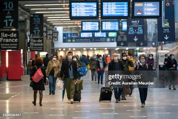 Travelers wearing face masks walk to their train at Gare Montparnasse after travel restrictions were relaxed during the Coronavirus pandemic on May...