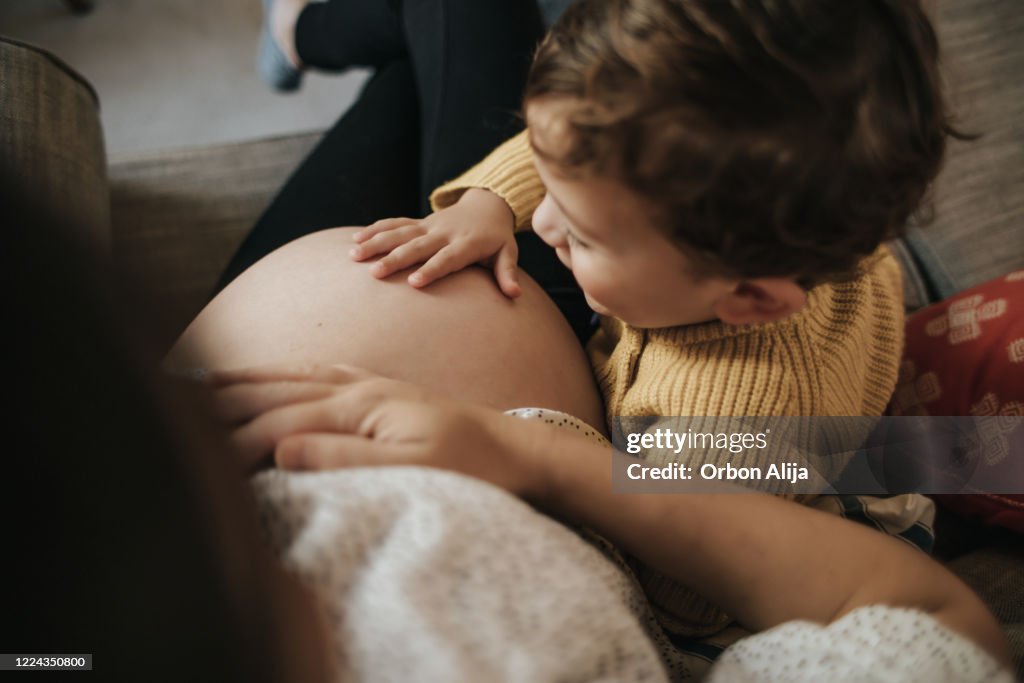 Junge berührt den Bauch seiner schwangeren Mutter