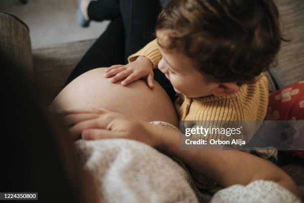 boy touching his pregnant mother's belly - woman kiss stock pictures, royalty-free photos & images