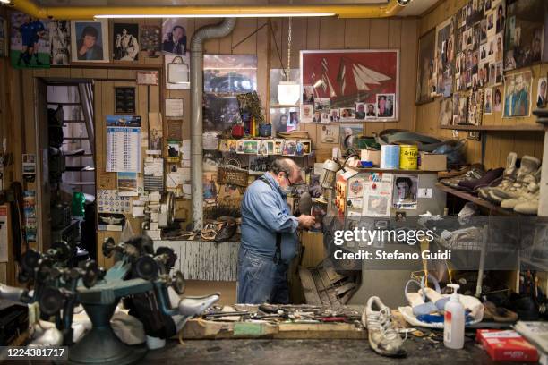 Pietro Agnano, historical shoemaker for more than 40 years in the Vanchiglia area of Turin, wears a protective mask while working in his shop on May...