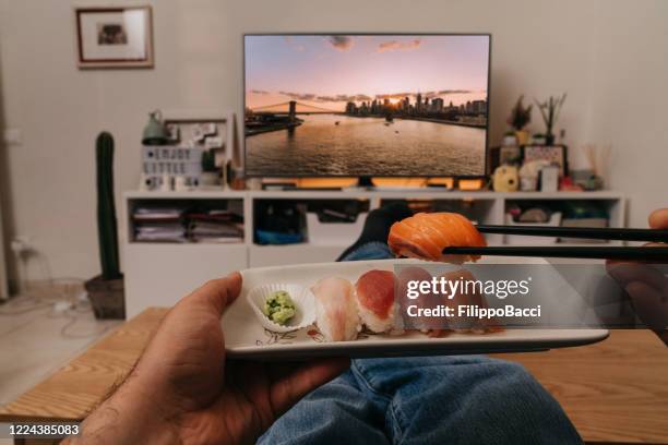 man is watching a movie on the tv while he's eating sushi - reportage home stock pictures, royalty-free photos & images