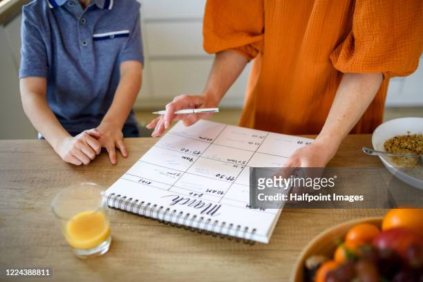 unrecognizable mother with small son indoors in kitchen, planning. - week stock pictures, royalty-free photos & images