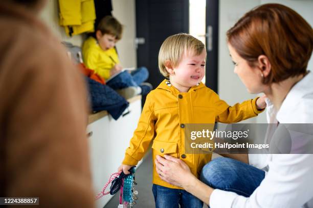 mother with small children indoors in hall in the morning at home, preparing for school. - fighting group stockfoto's en -beelden