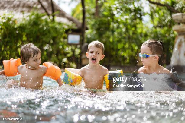 group of happy children playing in the swimming pool on a sunset - arm band stock pictures, royalty-free photos & images