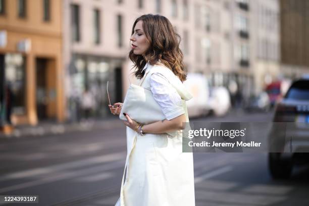 Masha Sedgwick wearing Jil Sander clutch, Orgreen shades, Baum & Pferdgarten dress, Nobi Talai coat on May 06, 2020 in Berlin, Germany.