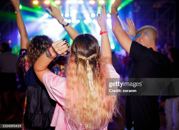 three friends cheering at outdoor music festival facing stage - long hair back stock pictures, royalty-free photos & images