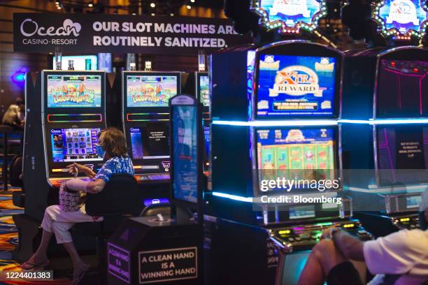 Visitor wearing a protective mask sits at a slot machine at the Ocean Casino Resort in Atlantic City, New Jersey, U.S., on Thursday, July 2, 2020....