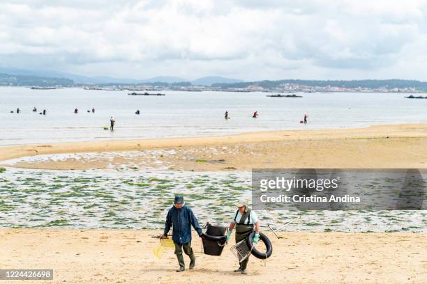 Shellfishermen leave the beach after picking up clams on May 12, 2020 in A Pobra do Caramiñal, Spain. The shellfishermen of A Pobra do Caramiñal...