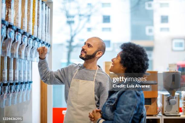 owner assisting smiling mature female zero waste customer - supermarket customer stock pictures, royalty-free photos & images