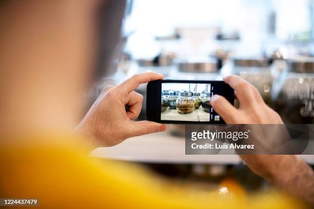 midsection of male customer photographing spice jar - horizontal stock-fotos und bilder