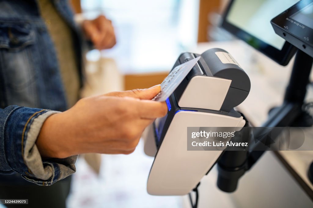 Woman using credit card for contactless payment at checkout