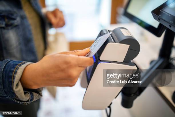 woman using credit card for contactless payment at checkout - credit card stock-fotos und bilder