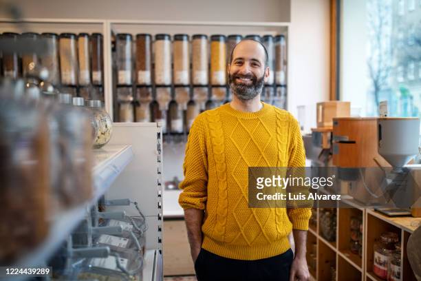 smiling customer standing by rack at zero waste store - yellow stock-fotos und bilder